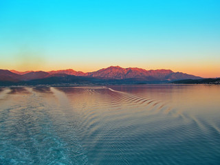 Kotor bay, Montenegro, Europe. Beautiful landscape of the sea, coastline, mountains and sky. View from a cruise ship that leaves a trail of waves on a calm water surface. 