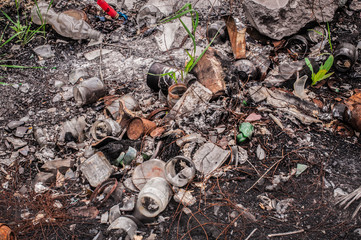 Burned garbage on soil with green grass growing throuh it