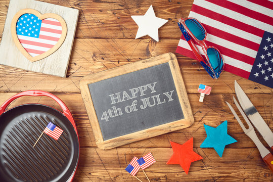 Happy Independence Day, 4th of July celebration concept with chalkboard, USA flag and barbeque grill  on wooden background.