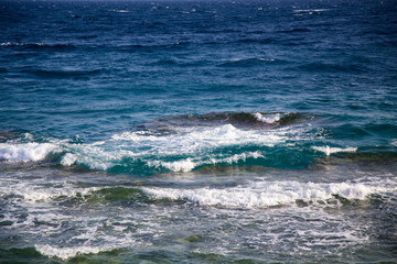 Fototapeta premium Blue clear water. Beautiful blue sea wave photograph close up. Beach vacation at sea or ocean. Background to insert images and text. Tourism, travel. Big wave with a white hat