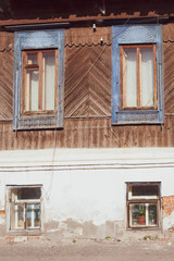 the facade of an old,rooted in the ground house with wooden Windows and trim