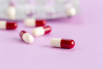 Red and white capsules on a colored background