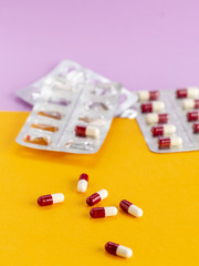 Blister packaging of red and white capsules on a colored background
