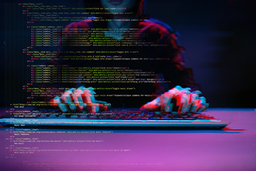 Hacker working with computer in dark room with digital interface around. Image with glitch effect.