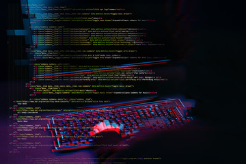 Hacker working with computer in dark room with digital interface around. Image with glitch effect.