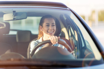 Happy woman driving a car and smiling - Powered by Adobe