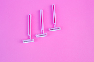 Three women's razors pink color on an isolated pink background.