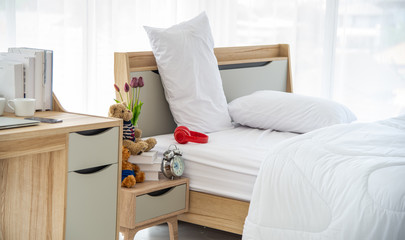 The modern or minimal interior bedroom design decorated with comfortable  double bed, white bedding such as blanket, pillows and wooden furniture