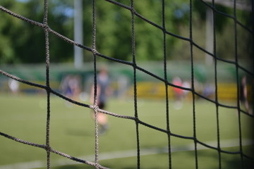 Grid of a football goal with a blurred view of a football field