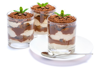 Classic tiramisu dessert in a glass on plate with spoon isolated on a white with clipping path