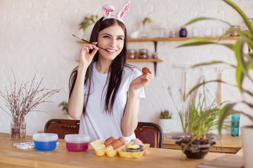 Beautiful, young woman paints eggs for Easter. Handmade, prepare for the holiday. Palm Sunday.