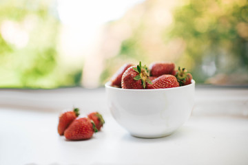 sweet strawberries in a saucer on a summer window