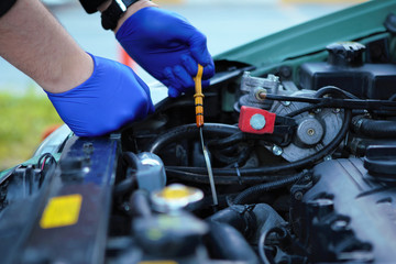 Obraz premium Car Mechanic Checking the Cars Oil Level with a Dipstick 