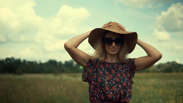 Romantic Woman Walking On Field.Sexy Woman On Sunglasses.Woman In Hat Walking On Field.Woman In Hat.Wicker Hat.Blonde Girl On Sunglasses.Girl Relaxing.Girl Walks Through Field. Pretty Ledy In Dress.