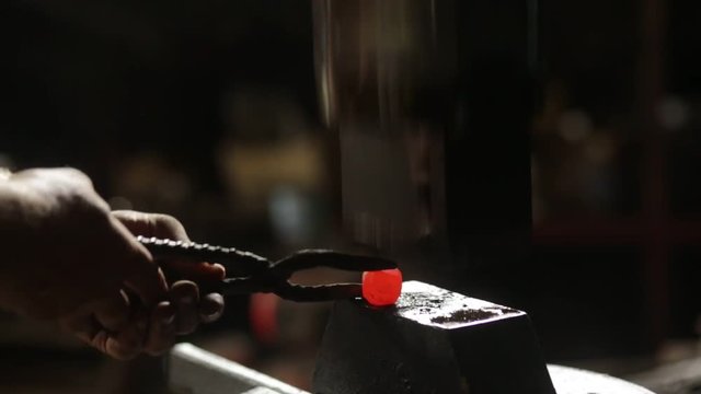 The blacksmith in the blacksmith makes a tip of incandescent iron