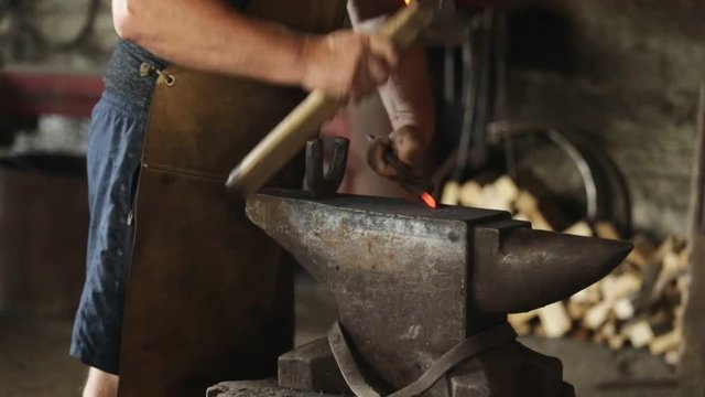 The blacksmith in the blacksmith makes a tip of incandescent iron