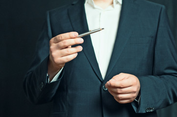 Businessman is holding a presentation or explaining, gesturing with a silver pen in his hand