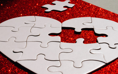White heart shaped puzzle on red.