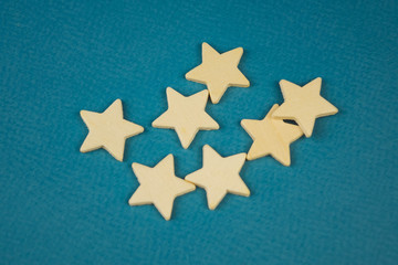 Fototapeta na wymiar A bunch of wooden stars on a blue background chaotically scattered.
