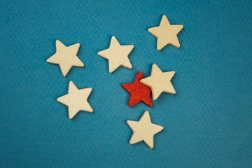 Fototapeta na wymiar a bunch of wooden stars and one of them is highlighted in red. subject on blue background