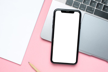 Mobile phone blank screen , laptop and business notebook on pink background with copy space for your text.Woman working desk.