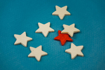 a bunch of wooden stars and one of them is highlighted in red. subject on blue background