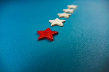a bunch of wooden stars and one of them is highlighted in red. subject on blue background