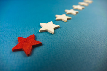 a bunch of wooden stars and one of them is highlighted in red. subject on blue background