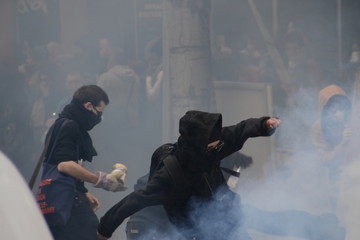 Masked protesters throw projectiles at police in response to tear gas