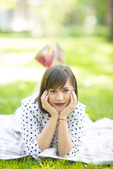 Young woman in retro dress lying on blanket in park