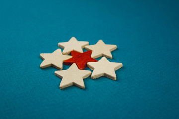 Fototapeta na wymiar a bunch of wooden stars and one of them is highlighted in red. subject on blue background.
