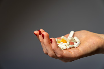 Medicine tablets and pills of different color on open pretty female hand with red fingernails on...
