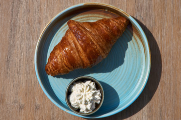 Breakfast concept. Morning, Healthy breakfast. Freshly baked croissants with cream cheese in a blue plate on the table copy space, selective focus.