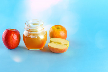 Rosh hashanah jewish holiday concept. Apples and honey jar for jewish new year holiday over blue background. Healthy food.Bokeh lights.