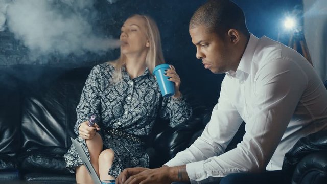 Group of Mixed race People in Cafe. Busy Man using laptop, woman smoking vape and drinking coffee