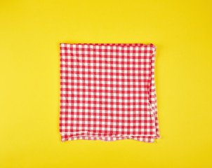 folded red kitchen towel in a cage on a yellow background