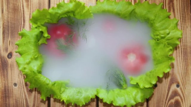 The dish is decorated with lettuce are tomatoes, cucumber and radishes covered in morning fog. A light morning breeze blows the fog off the dish.