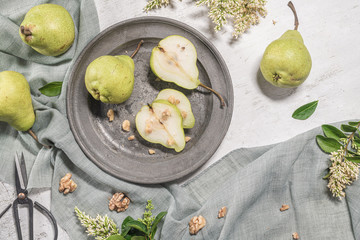 Tasty pears with nuts. A table decorated with flowers and a plate of pears cut into the plate