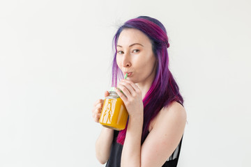 Cute young mixed race hipster girl with colored hair drinks fruit smoothie before starting a yoga class on a white background. Healthy lifestyle concept. Copyspase.