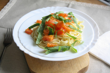 Spaghetti with tomatoes and spinach on a white plate