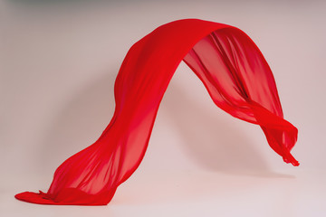 Red fabric on a white background. Levitation of red fabric in the photo studio. Soaring piece of...
