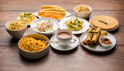 Fototapeta na wymiar Group of Gujarati snacks like jalebi-fafda, thepla, khaman dhokla, aloo bhujiya, khandvi,khakra, dahi vada, gathiya with hot tea
