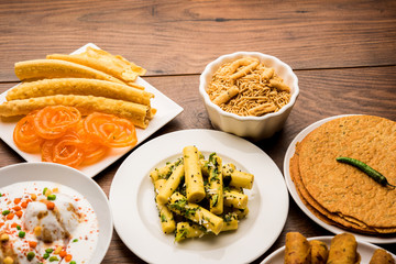 Group of Gujarati snacks like jalebi-fafda, thepla, khaman dhokla, aloo bhujiya, khandvi,khakra, dahi vada, gathiya with hot tea