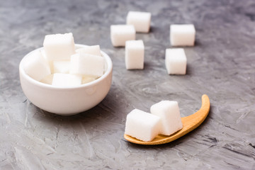 Sugar-free sugar cubes in a white bowl and in a wooden spoon on a table