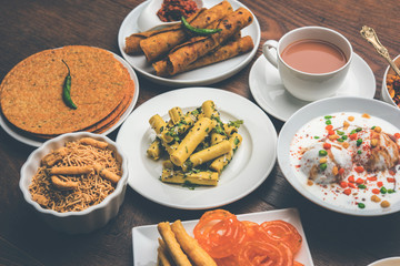 Group of Gujarati snacks like jalebi-fafda, thepla, khaman dhokla, aloo bhujiya, khandvi,khakra, dahi vada, gathiya with hot tea