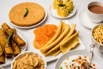 Group of Gujarati snacks like jalebi-fafda, thepla, khaman dhokla, aloo bhujiya, khandvi,khakra, dahi vada, gathiya with hot tea