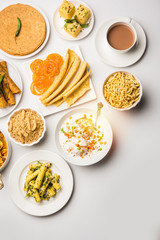 Group of Gujarati snacks like jalebi-fafda, thepla, khaman dhokla, aloo bhujiya, khandvi,khakra, dahi vada, gathiya with hot tea