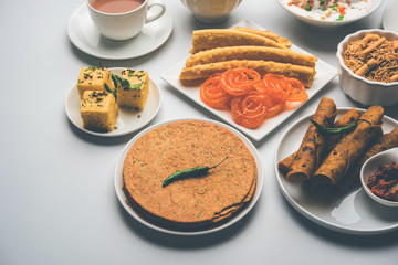 Group of Gujarati snacks like jalebi-fafda, thepla, khaman dhokla, aloo bhujiya, khandvi,khakra, dahi vada, gathiya with hot tea