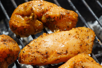 Marinated chicken pieces on the grid of a barbecue