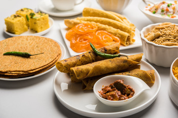 Group of Gujarati snacks like jalebi-fafda, thepla, khaman dhokla, aloo bhujiya, khandvi,khakra, dahi vada, gathiya with hot tea